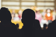 Silhouettes of parents watching a kids performance
