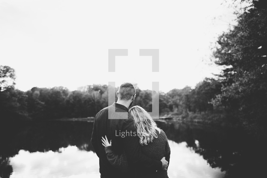 couple hugging standing in front of a pond 