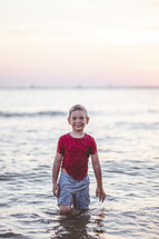 a happy boy standing in the ocean 