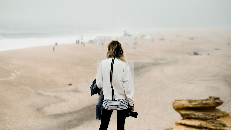 woman with a camera walking on a beach 