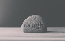 a rock with the word laugh
