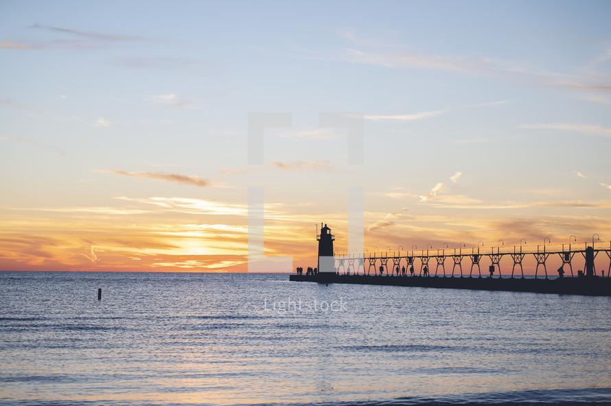 Lighthouse at the end of pier at sunset
