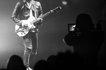 Camera man filming man playing guitar