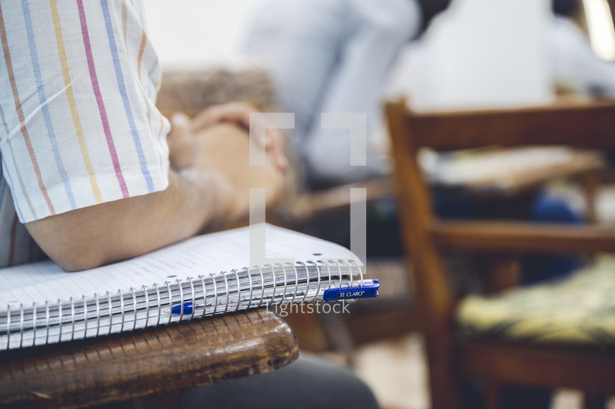 man sitting at a desk with a notebook in a classroom 