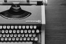 A black-and-white version of the old orange typewriter in this series. Close-up of keys, on wood backdrop.