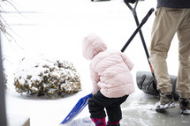 a little girl shoveling snow in winter 