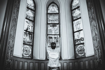 teen boy kneeling in worship in front of stained glass window 