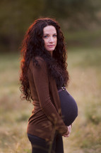Pregnant woman standing outside.