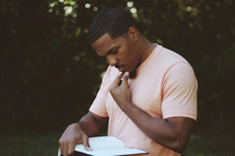Man reading the Bible outdoors.