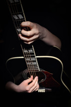 Young Woman Hugging With Her Hands Guitar, Isolated On Black