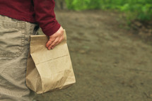 a child carrying a brown lunch bag