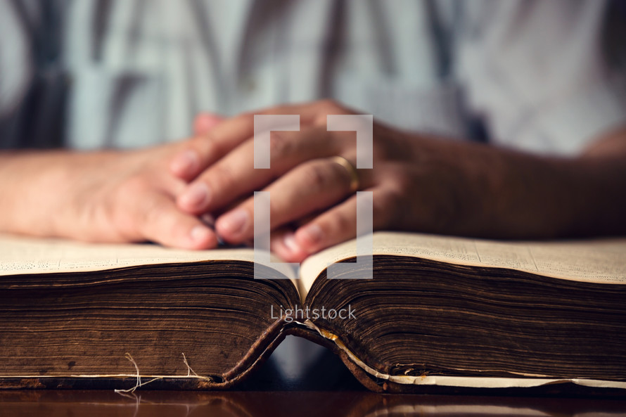 hands in prayer over the pages of a Bible 