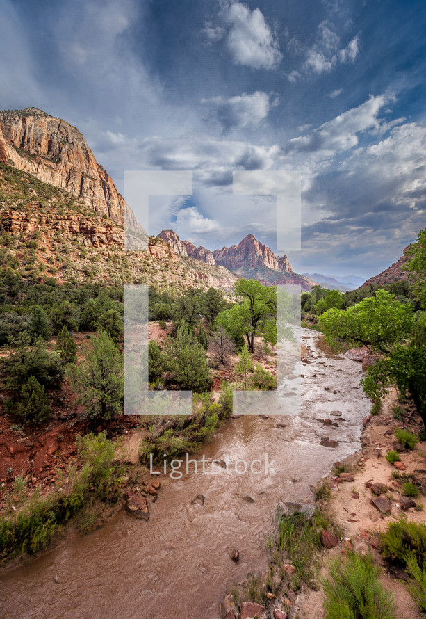 Captured from atop a bridge, Zion's Virgin river leads to The Watchman towering high in the hazy distance. 