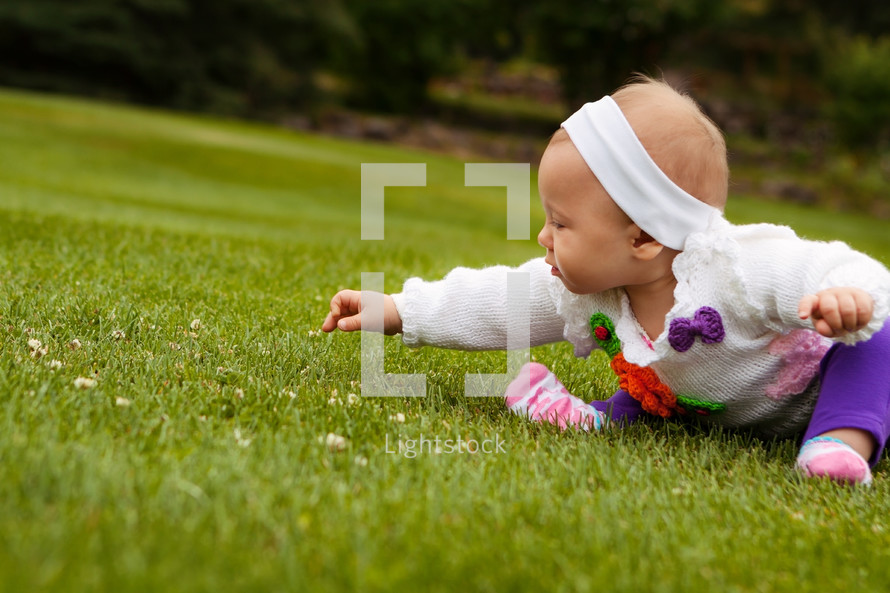 Infant girl picking flowers in the grass 
