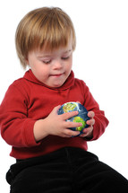 Young boy sitting on the floor holding a ball