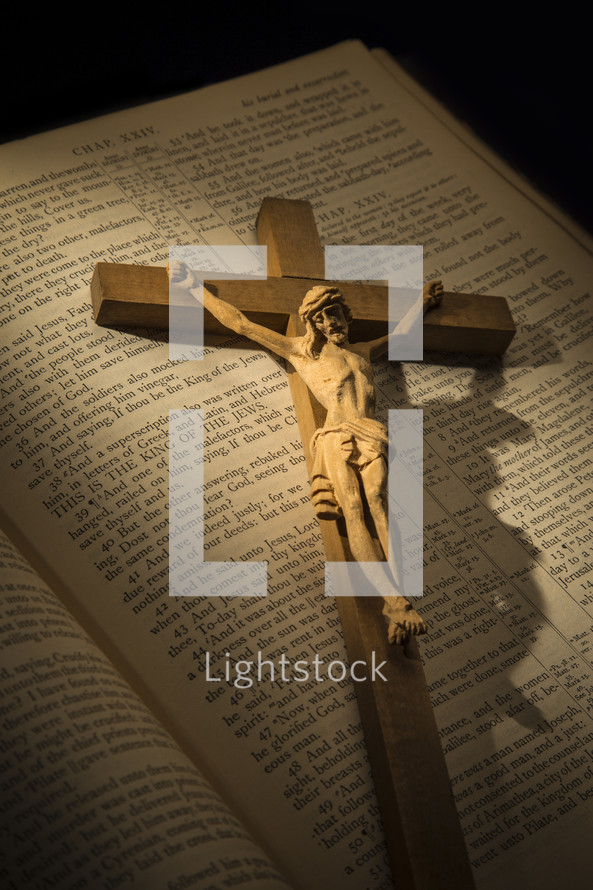 a crucifix on the pages of a Bible opened to the passion account