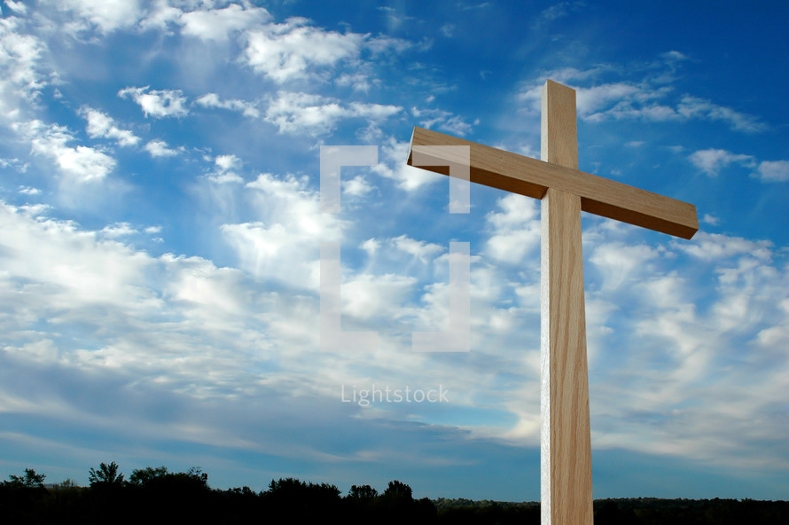 wood cross against a blue sky with clouds 