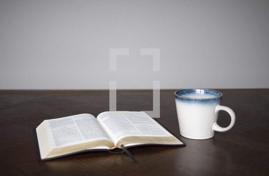 open Bible and coffee mug on a table ready for a Bible study, a small group meeting or teaching moment, as well, they could be preparing for discipleship.