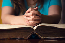 woman in prayer over the pages of a Bible 