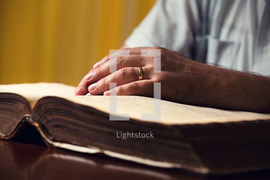 hands over the pages of a Bible 