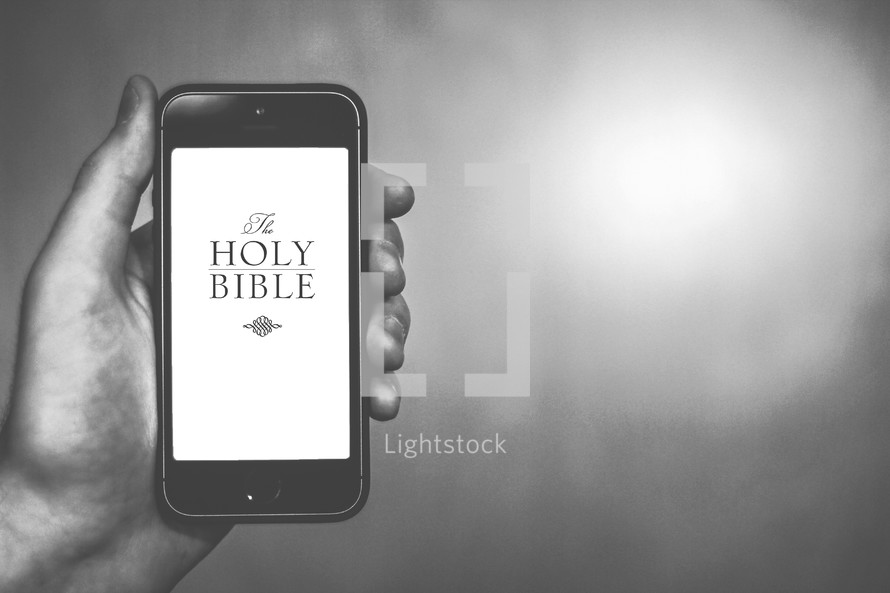 Hand holding a cell phone; viewing the Holy Bible online.