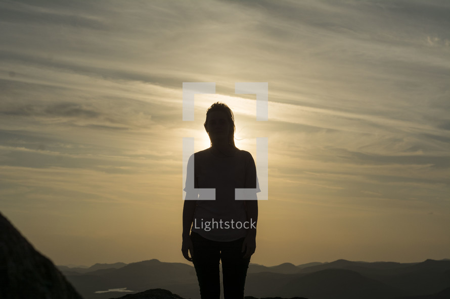 silhouette of a woman standing on a mountain top 