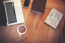 laptop, computer, wood floor, wood table, open Bible, Bible, journal, cup, coffee, mug, cellphone, phone 