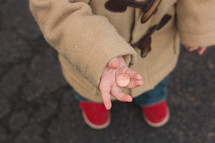 Child standing outside holding a penny.