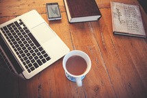 laptop, computer, wood floor, wood table, open Bible, Bible, journal, cup, cellphone 