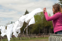 Woman hanging white clothes on a clothesline