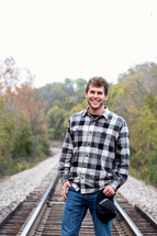young man standing on railroad tracks 
