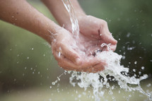 Pouring water splashing in cupped hands.
