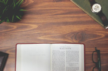 open Bible and reading glasses on a wood table - Matthew 