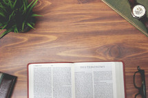 open Bible and reading glasses on a wood table - Deuteronomy 