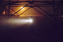 A man holding a flashlight in the dark fog
