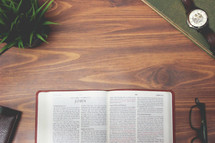 open Bible and reading glasses on a wood table - John