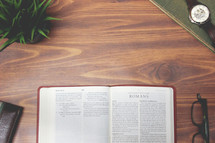 open Bible and reading glasses on a wood table - Romans 