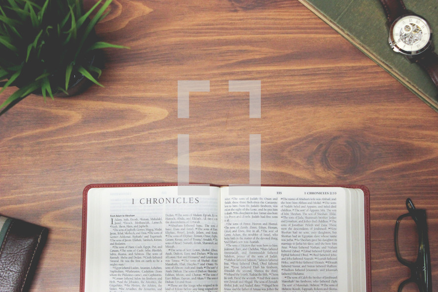 open Bible and reading glasses on a wood table - 1 Chronicles 