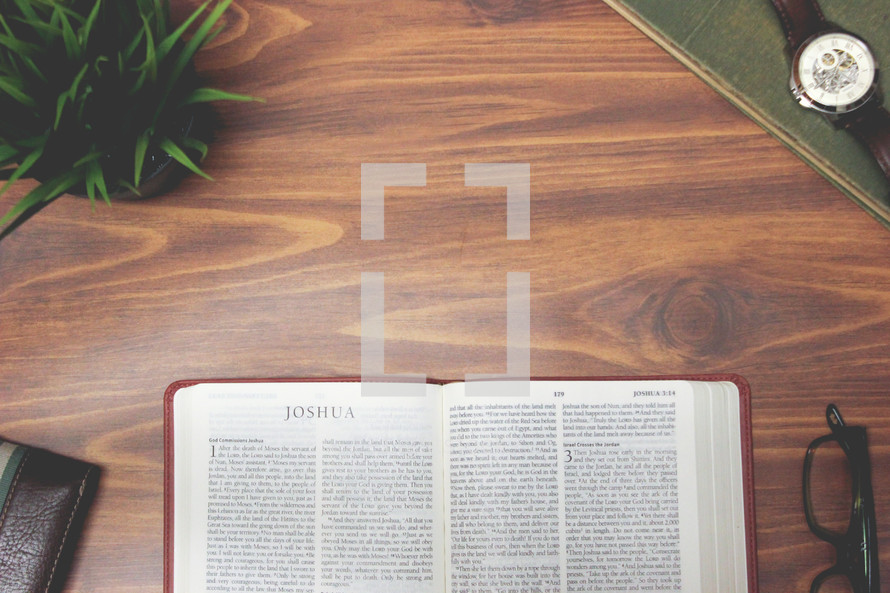 open Bible and reading glasses on a wood table - Joshua