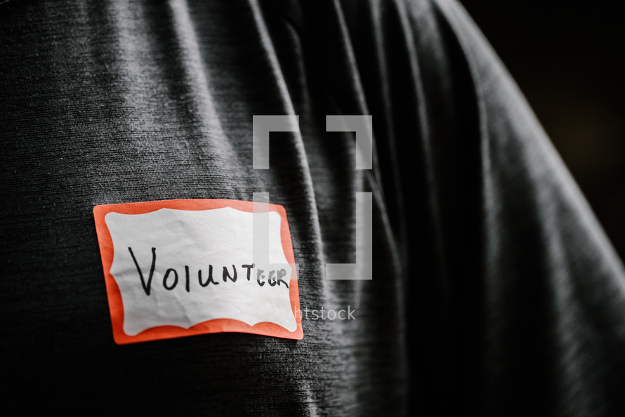 a man wearing a name badge with the word volunteer 