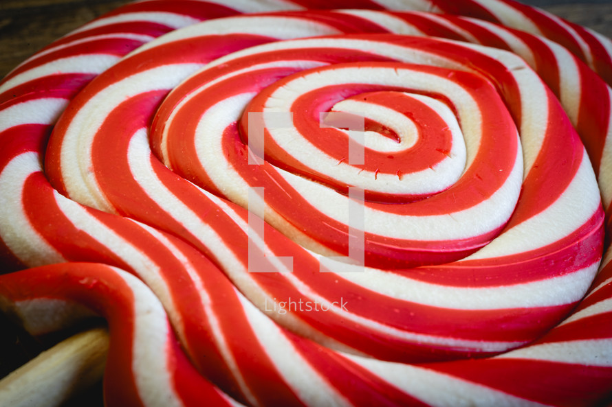 Close up from a Christmas lollypop on a wooden background. Red and white swirl. Background for Christmas.