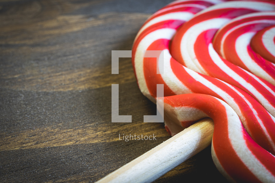 Close up from a Christmas lollypop on a wooden background. Red and white swirl. Background for Christmas.