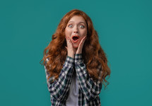 Surprised woman, she expresses WOW, cant believe. Impressed lady trying to get attention. Concept of sales, profitable offer. Excited ginger girl on blue background. High quality