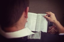 a man looking down reading a Bible 