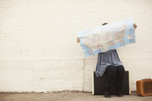 woman sitting on suitcases looking at a map 