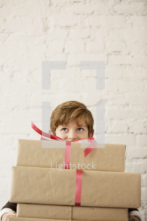 a young boy holding a stack of gifts.