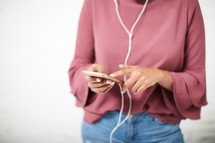 a woman listening to a cellphone with earbuds 