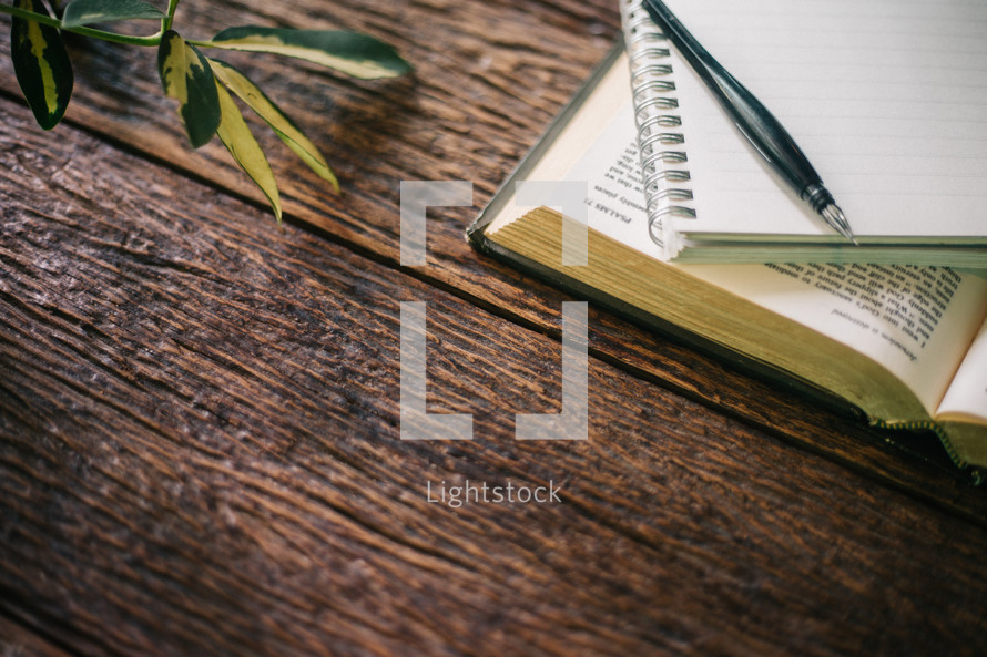 pencil, notebook, and open Bible on a wood background 