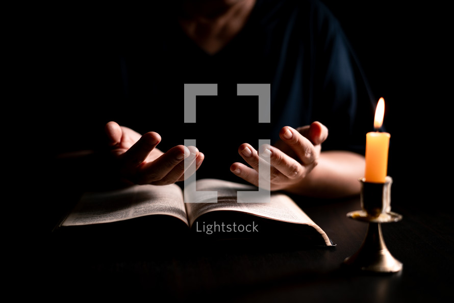 Bible and candlelight with praying woman