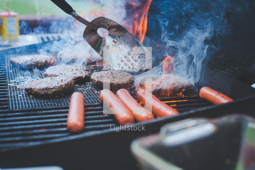 cooking hamburgers and hotdogs on a grill 
